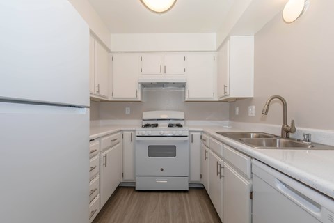 A white kitchen with a stove and sink.