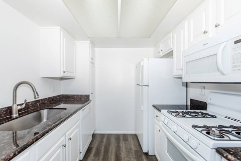 A kitchen with white cabinets and a black counter top.