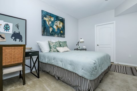 A bedroom with a bed, a chair, and a painting on the wall.