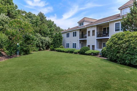 A large grassy area in front of a building with trees on the left.