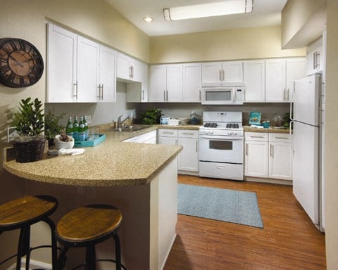 A kitchen with white cabinets and a granite countertop.