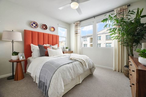 A bedroom with a large bed and a window with curtains.