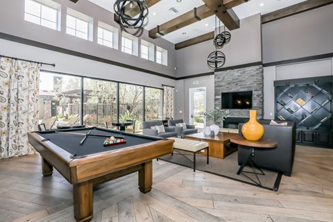 A pool table is in the middle of a room with a fireplace and a TV.