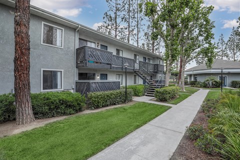 A concrete pathway leads to a building with a balcony.