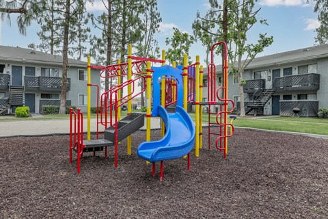 A playground with a blue slide and red and yellow climbing structures.