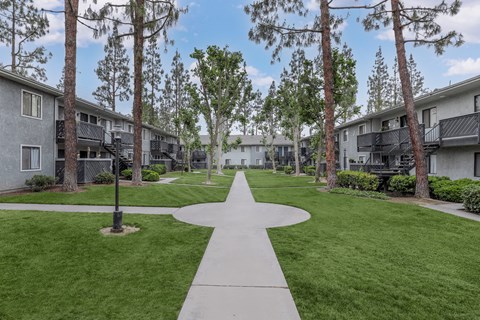 A pathway leads through a grassy area between two rows of buildings.