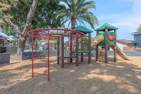 A playground with a red swing set and a green slide.
