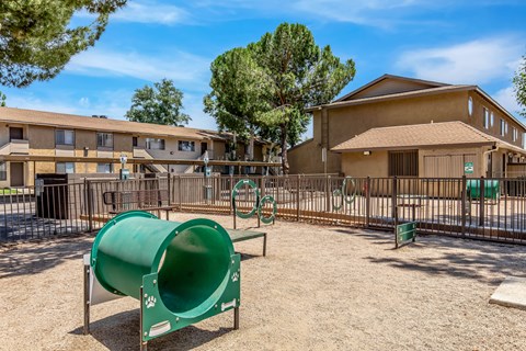 A playground with a green slide and a brown building in the background.