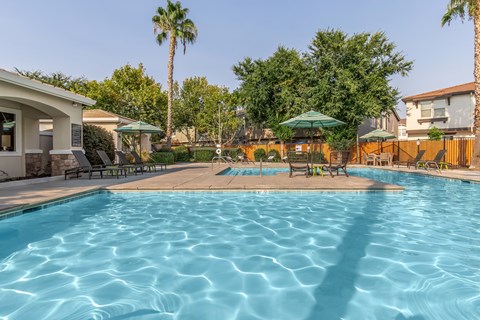A swimming pool surrounded by palm trees and a building.