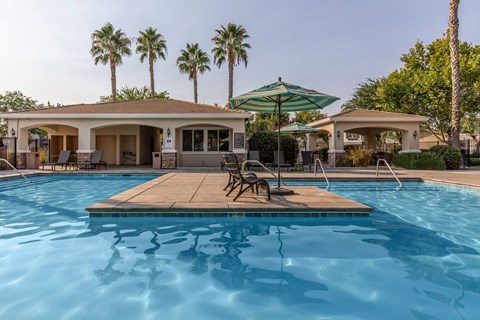 A pool with a wooden deck and a green umbrella.