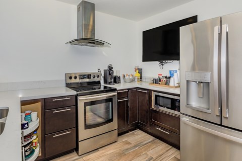 A modern kitchen with stainless steel appliances and wooden flooring.