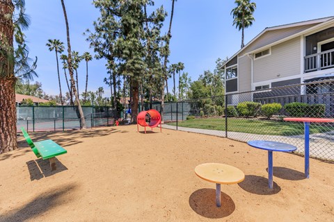 A playground with a red slide, green bench, and a yellow and blue table.
