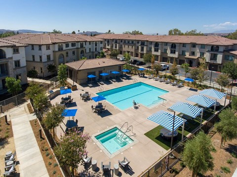 A large swimming pool surrounded by blue umbrellas and lounge chairs.