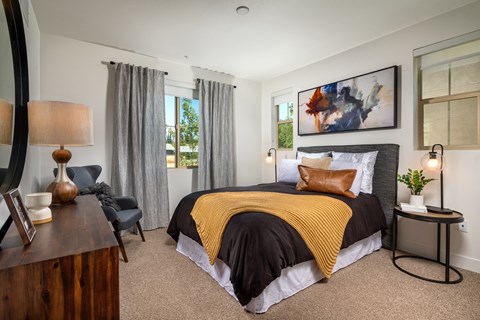 A bedroom with a bed covered in a black and yellow blanket.