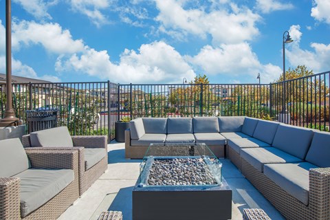 A patio with grey furniture and a glass table with rocks in it.