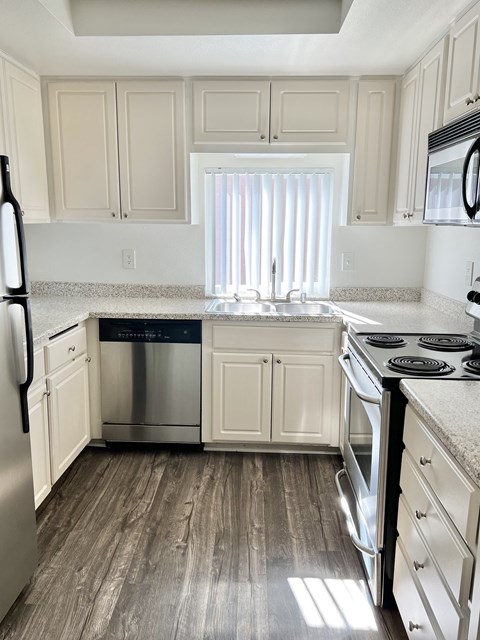 A kitchen with white cabinets and a stainless steel dishwasher.