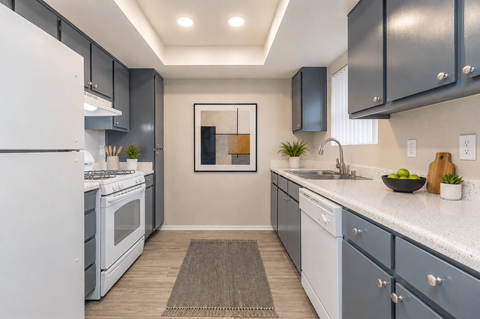 A modern kitchen with a white refrigerator and a white countertop.