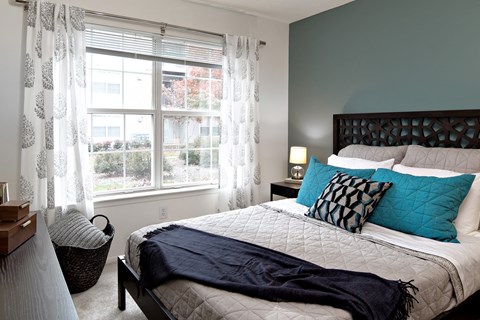 A bedroom with a large bed and a window with curtains.