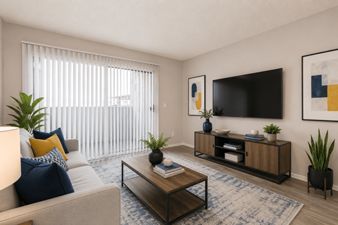 A living room with a grey couch, a wooden coffee table, and a flat screen TV mounted on the wall.