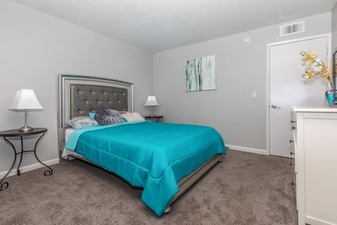 A bedroom with a bed, nightstand, and lamp.