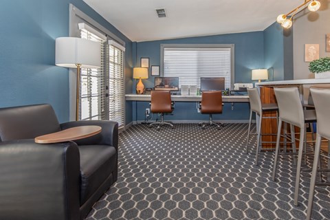A living room with a grey carpet and a black leather sofa.