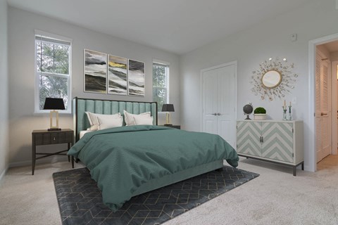 A bedroom with a bed, nightstand, and a wall hanging.