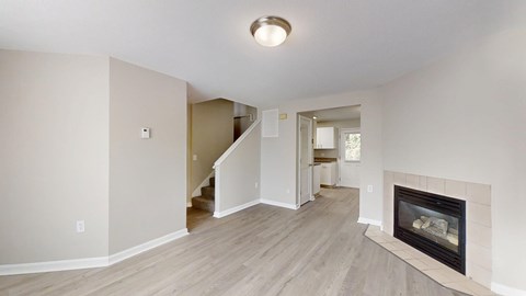 A living room with a fireplace and a staircase.
