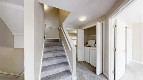 A staircase with a carpeted runner leads to a bedroom with a dresser and a wardrobe.