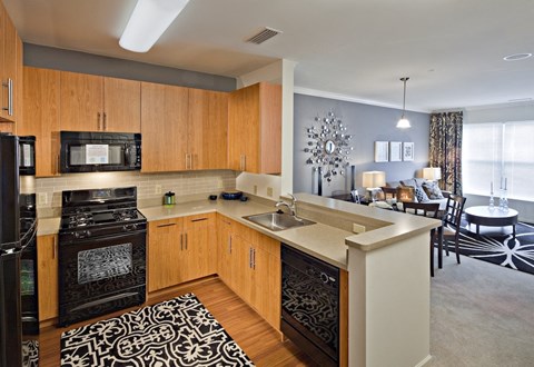 A modern kitchen with wooden cabinets and black appliances.