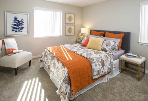 A bedroom with a large bed and a chair.