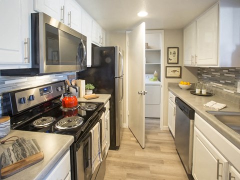 A kitchen with black and white appliances and wooden floors.