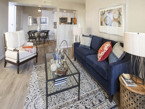 A living room with a blue couch and a glass coffee table.