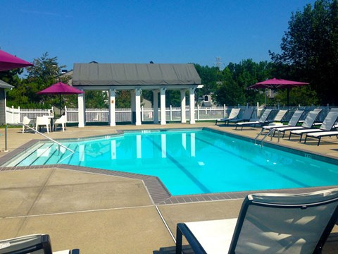 A pool with a white fence and a gazebo in the background.