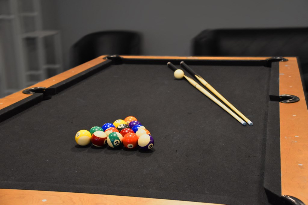 a pool table with billiard balls and a pair of cues