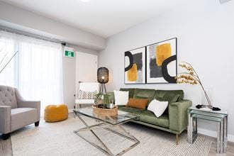 a living room with a green couch and a glass coffee table