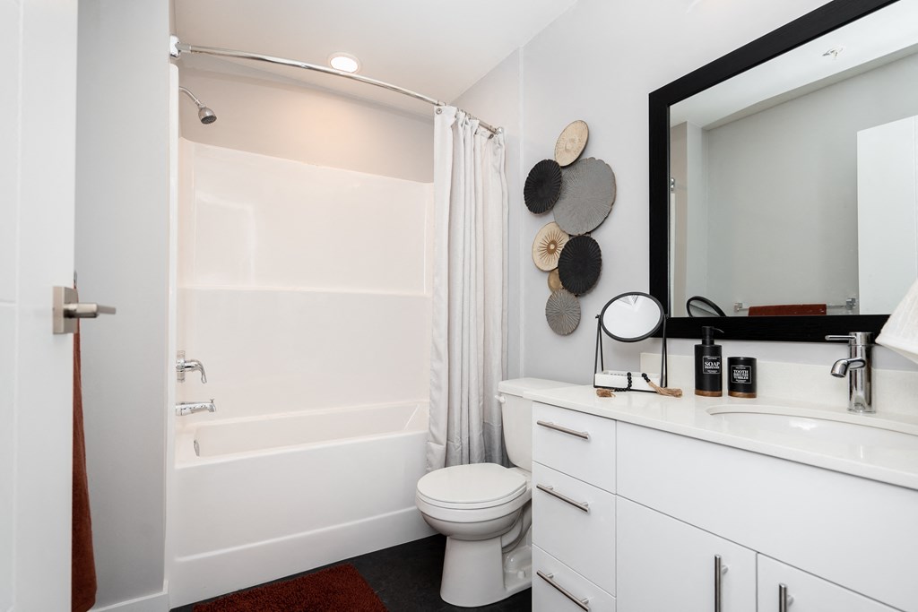 a bathroom with a white toilet next to a white bathtub with a shower curtain
