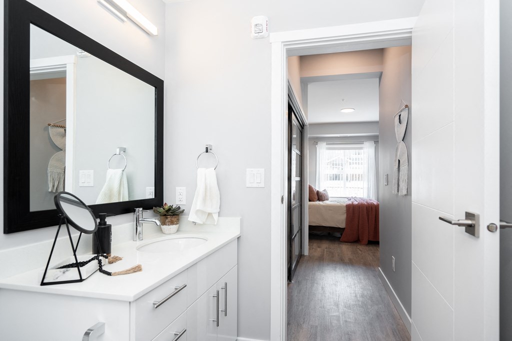 a bathroom with white cabinets and a white vanity with a black mirror
