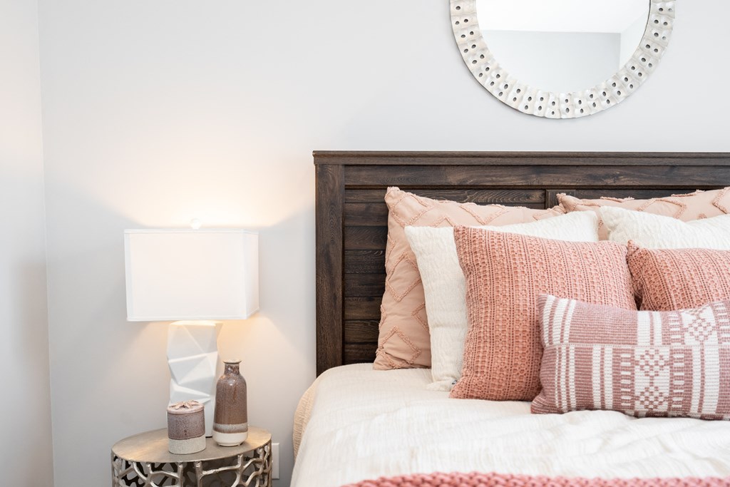 a bedroom with white walls and a bed with pink and white pillows