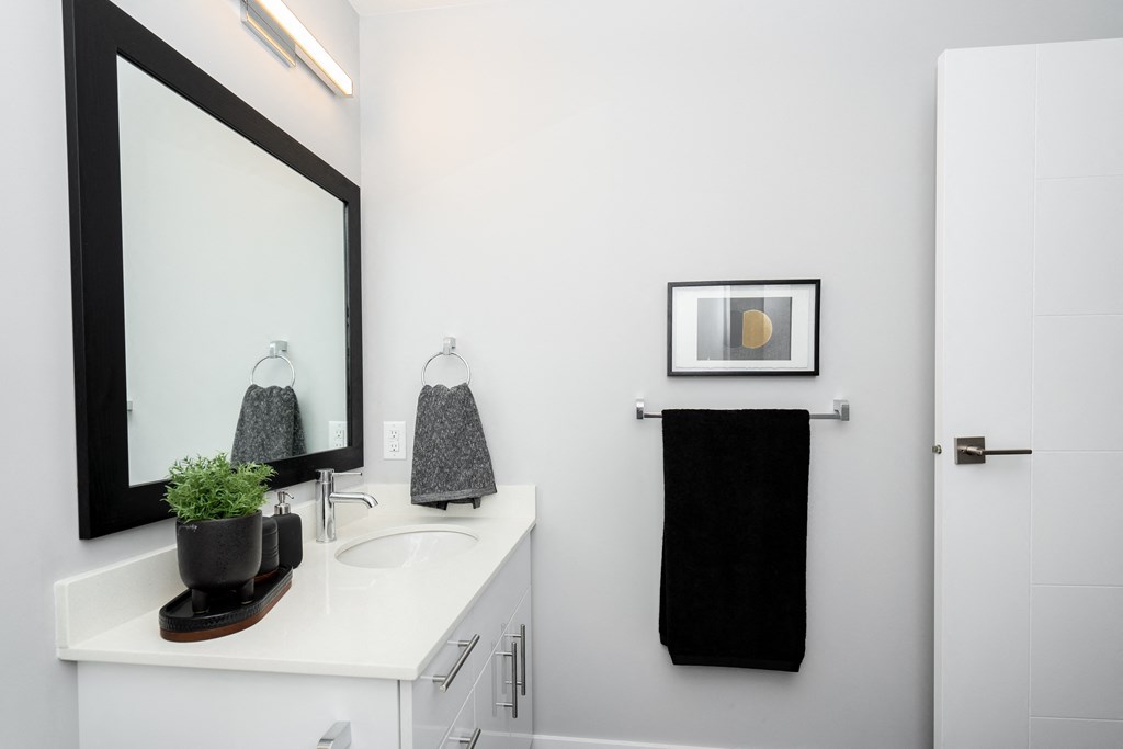 a small bathroom with a white countertop and a black towel rack