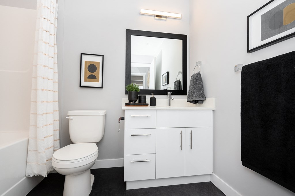 a small bathroom with a white vanity and toilet and a white bathtub with a shower curtain