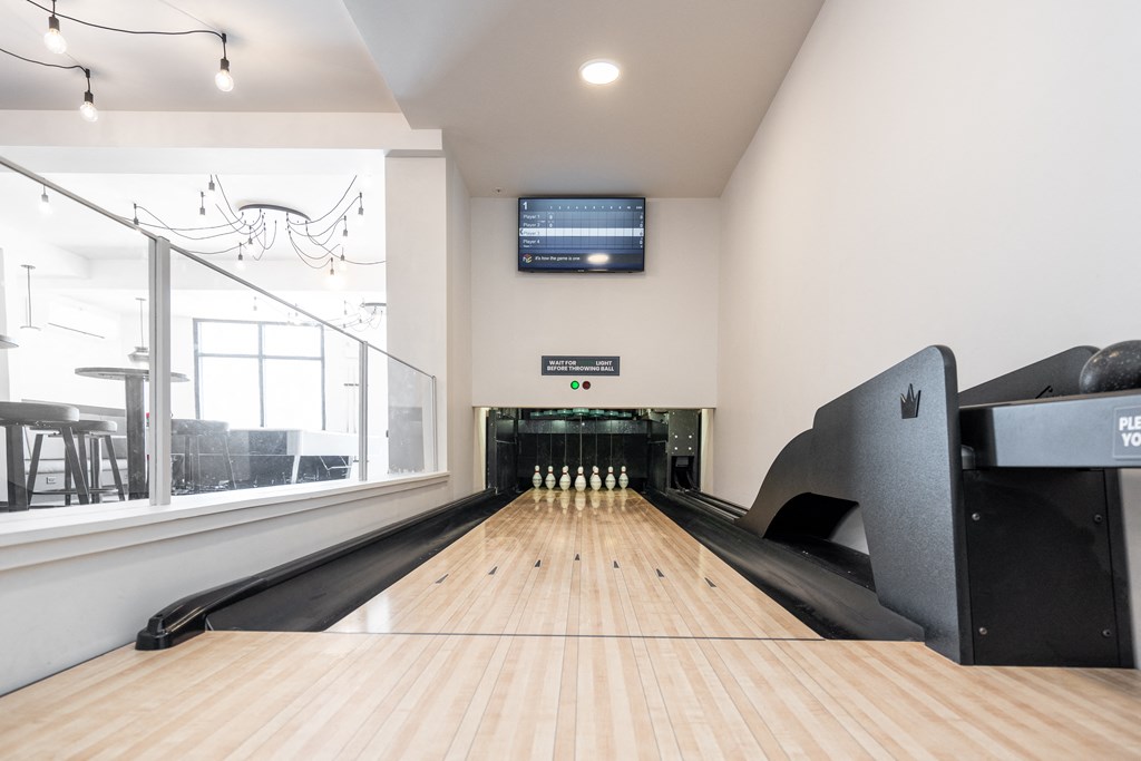 a bowling alley with bowling pins and a television on the wall
