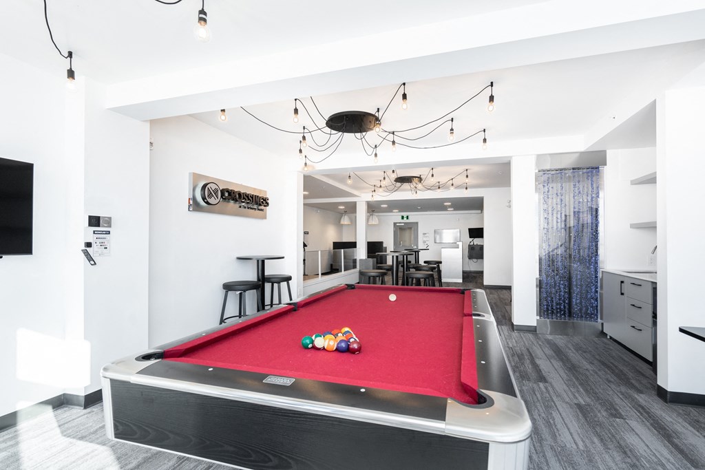 a red pool table in a living room with a bar and a television