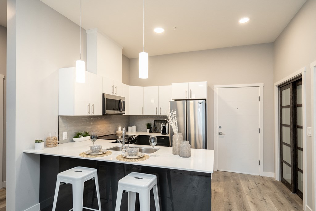 a kitchen with white cabinets and a counter top with bar stools