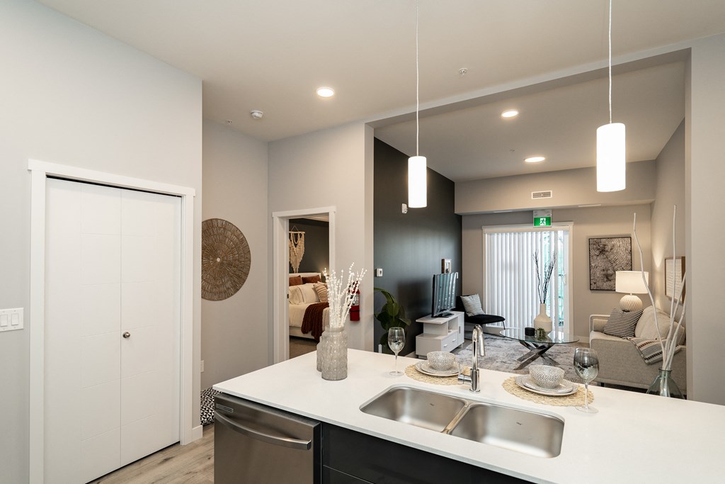 a kitchen and living room with a white counter top and a sink