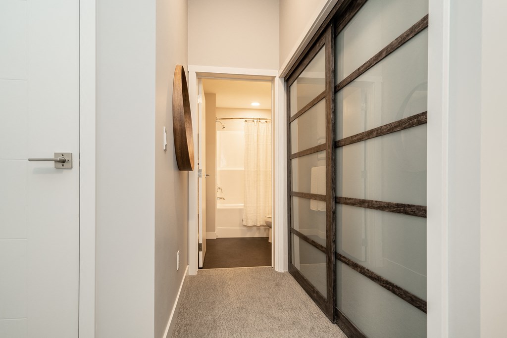 a walk in closet with a glass door and a bathroom in the background