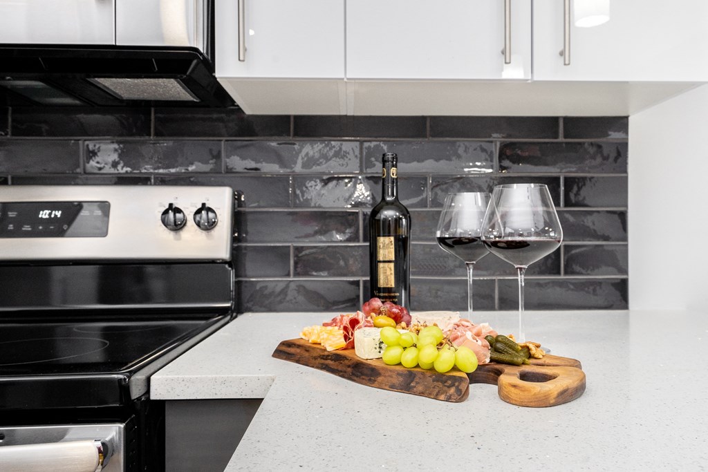a kitchen counter with wine glasses and a cutting board with food on it