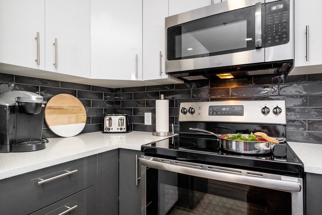 a kitchen with a stove and microwave and white cabinets