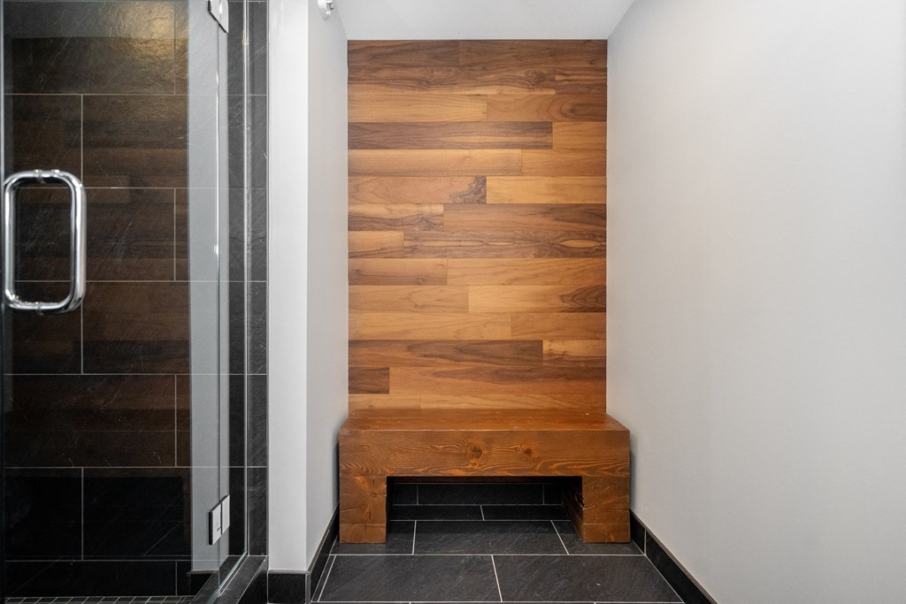 a wooden bench in a bathroom next to a shower