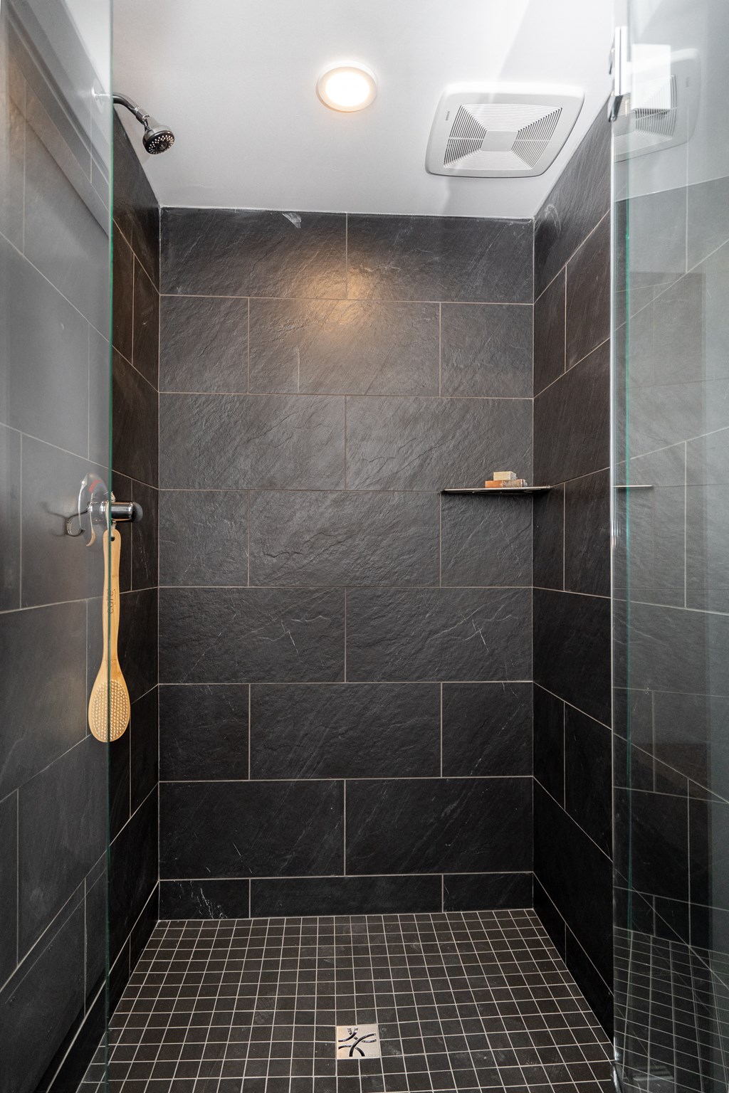 a black tiled bathroom with a shower and a guitar on the wall