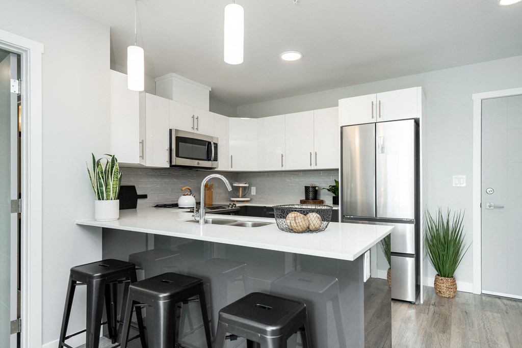 a kitchen with white cabinets and a counter top with bar stools